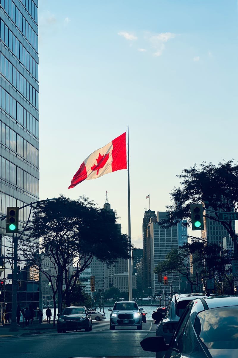 Cityscape of Windsor, Ontario, featuring the Canadian flag at twilight. Urban skyline with cars.