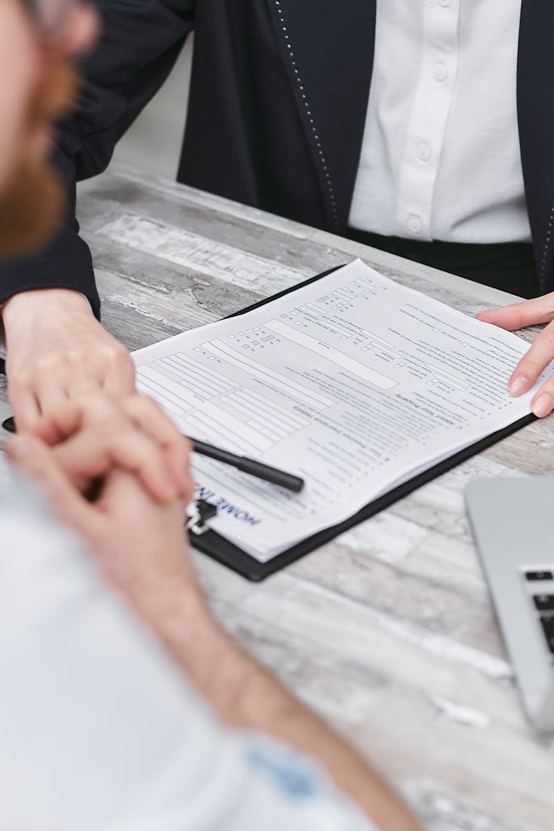 Two people in a business meeting reviewing documents on a clipboard.